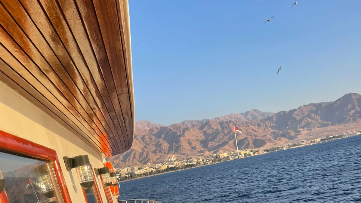 A tour boat in the Gulf of Aqaba with the town and mountains behind